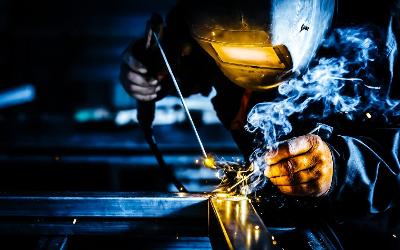 Professional mask protected welder man working on metal welding and sparks metal.