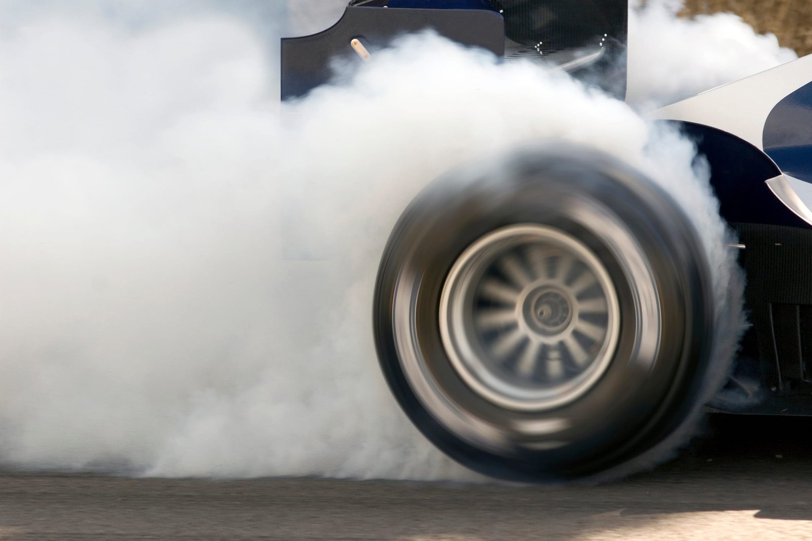 2006 Formula One Grand Prix car smoking its super slick tires. The Formula One Grand Prix car is engulfed in white smoke.